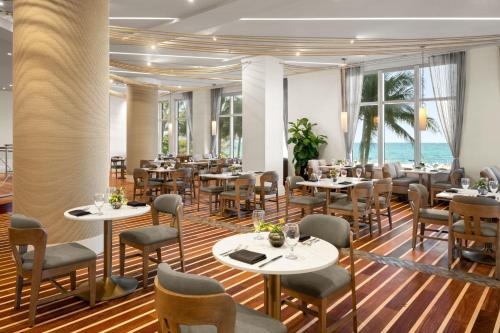 a restaurant with tables and chairs with the ocean in the background at Palm Beach Marriott Singer Island Beach Resort & Spa in Palm Beach Shores