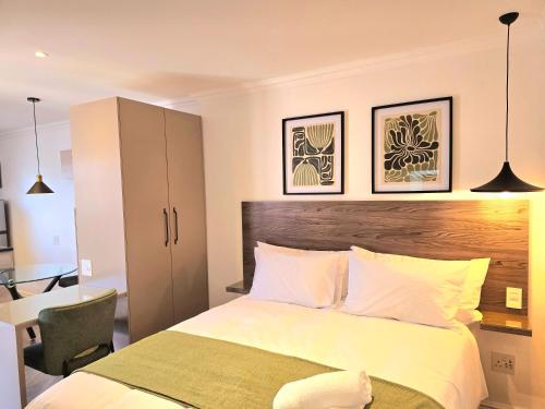 a bedroom with a bed and a desk with a chair at Hampton Collection Avenues - Cosy 2 Sleeper Studio Apartment in Durban