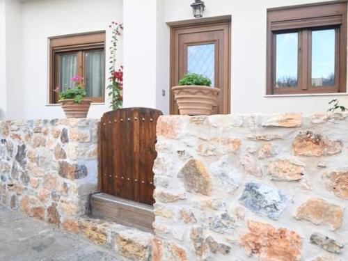 a stone wall in front of a house with two windows at Anezina Cretan hospitality in Heraklion