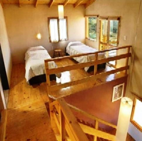 a small room with two beds and a staircase at Cabañas Wairoa Haus in Villa General Belgrano
