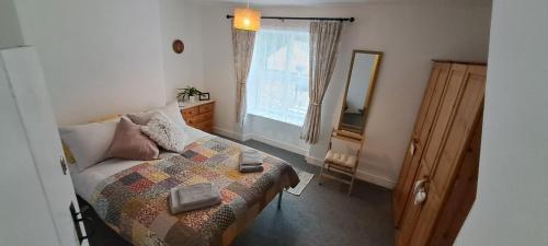 a bedroom with a bed and a mirror and a window at Charming Lincoln Cottage Family & Pet-Friendly in Lincoln
