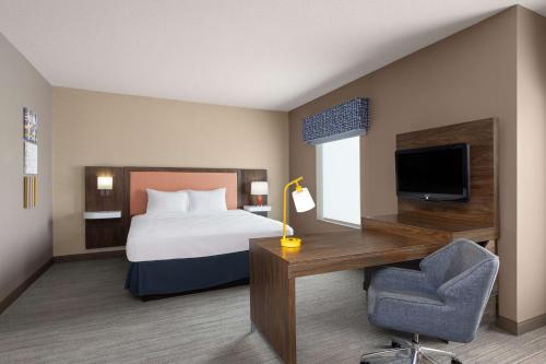 a hotel room with a bed and a desk and a television at Hampton Inn & Suites Harrisburg in Harrisburg