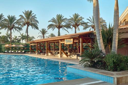 a resort with a swimming pool and palm trees at Hilton Alexandria King's Ranch Hotel in Alexandria