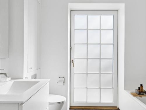 a white bathroom with a toilet and a glass door at Sanders Swan - Marvellous villa close to the center of Copenhagen in Copenhagen