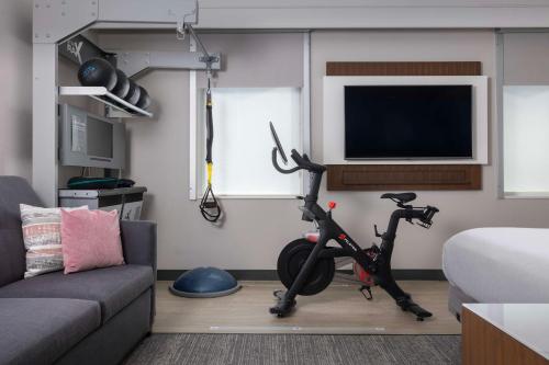 a living room with a exercise bike and a tv at Embassy Suites By Hilton Knoxville Downtown in Knoxville