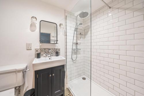 une salle de bain blanche avec un lavabo et une douche dans l'établissement Poacher's Cottage, à Dorchester