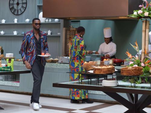 a man holding a plate in a kitchen with two chefs at Pullman Nairobi Upper Hill in Nairobi