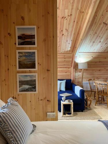 a bedroom with a blue couch and a table at Sandy Meadow Escapes in Achmelvich