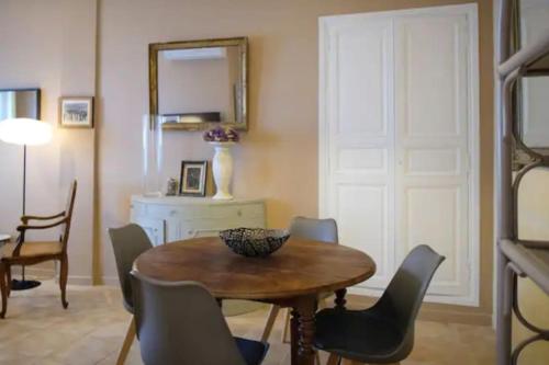 une salle à manger avec une table, des chaises et un miroir dans l'établissement Les Arènes Quartier La Roquette, à Arles