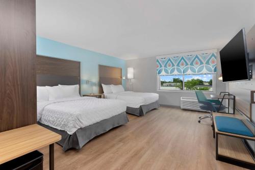 a hotel room with two beds and a flat screen tv at Tru By Hilton Lincoln East in Lincoln
