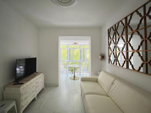 a living room with a couch and a tv at El Jardín de María Luisa Suites in Burgos