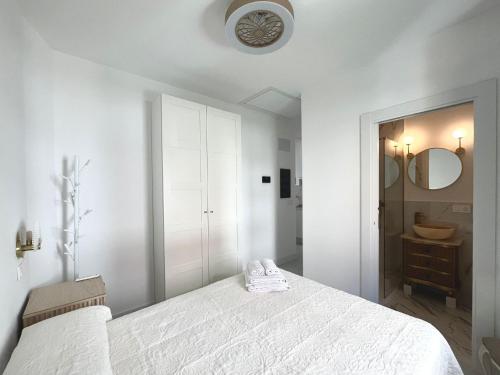 a white bedroom with a bed and a mirror at El Jardín de María Luisa Suites in Burgos