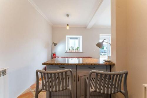 a kitchen with two chairs and an island with a sink at Nazare Townhouse near Lighthouse & Big Waves in Nazaré