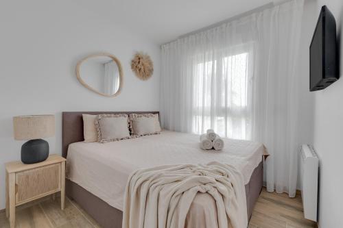 a white bedroom with a bed and a mirror at Apartment Laura Residence Bali in Alicante
