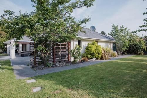 a house with a tree in front of a yard at Hidden Gem of Christchurch - Sleeps 13 in Christchurch