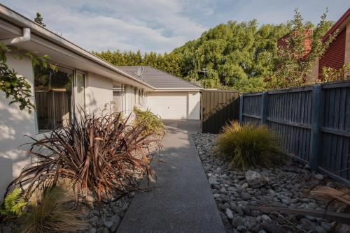 a house with a fence and a gravel driveway at Hidden Gem of Christchurch - Sleeps 13 in Christchurch