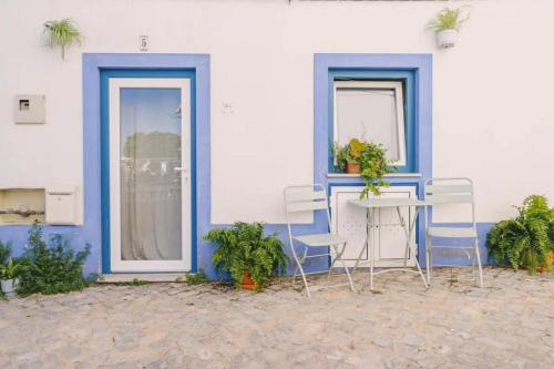 a table and chairs in front of a blue and white building at Nazare Townhouse near Lighthouse & Big Waves in Nazaré