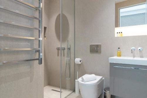a bathroom with a shower and a toilet and a sink at Wells Court by Aeria Apartments in London