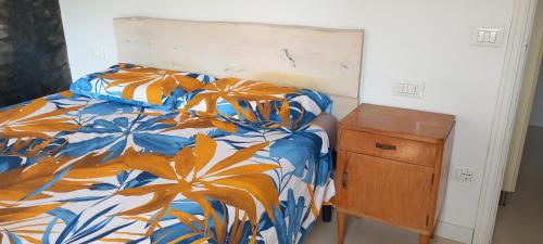 a bed with a colorful comforter and a wooden night stand at Da Gemma in Alano di Piave