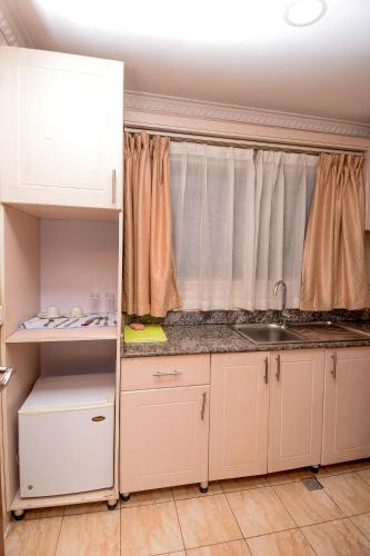 a kitchen with white cabinets and a sink and a window at Hill View Hotel Kiyovu in Kigali