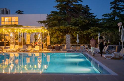 a couple walking by a swimming pool at night at Bluesun Hotel Borak in Bol
