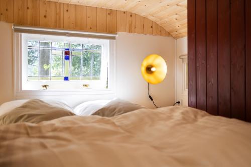 a bedroom with a bed with a window and a lamp at Wegdromen op de Veluwe in romantische rode pipowagen in Epe