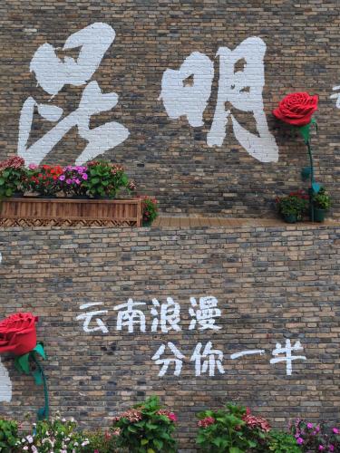 a brick wall with flowers and writing on it at Nostalgia S Hotel Kunming Old Street 时光漫步S酒店 昆明火车北站穿心鼓楼地铁站店 Free fresh ground coffee,Free laundry service in Kunming