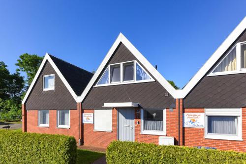 a red brick house with a black roof at Ferienhaus Heimathafen in Bensersiel