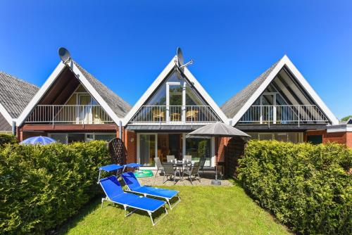 a house with two blue chairs and an umbrella at Ferienhaus Heimathafen in Bensersiel