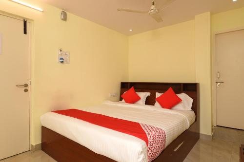 a bedroom with a large bed with red pillows at Hotel O Andhra Pradesh Hotels Association in Vijayawada