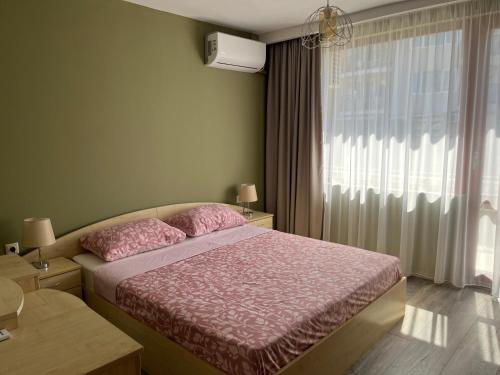 a bedroom with a bed with pink sheets and a window at Одеса 37 in Sozopol