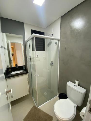 a bathroom with a toilet and a glass shower at RCM Vilas - Apartamento 505 in Joinville