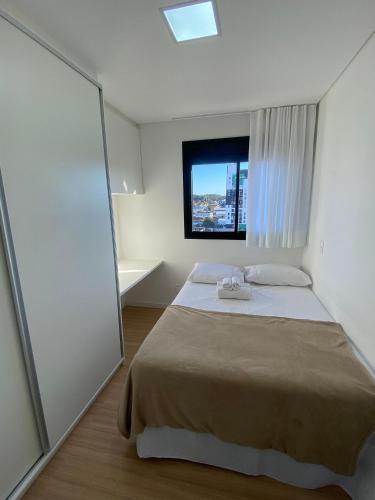 a bedroom with a large bed with a window at RCM Vilas - Apartamento 505 in Joinville