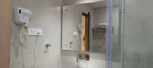 a bathroom with a mirror and a phone on the wall at Hotel Lee Garden Near to Blue Flag Beach 500 Mtrs in Puri