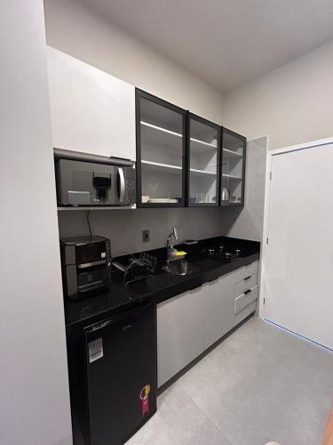 a kitchen with a black counter top and a microwave at Uni Tamari 405 in Cabedelo