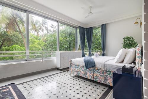 a bedroom with a bed and a large window at Verona by Vianaar Luxe Garden Pool Villa Assagao in Goa