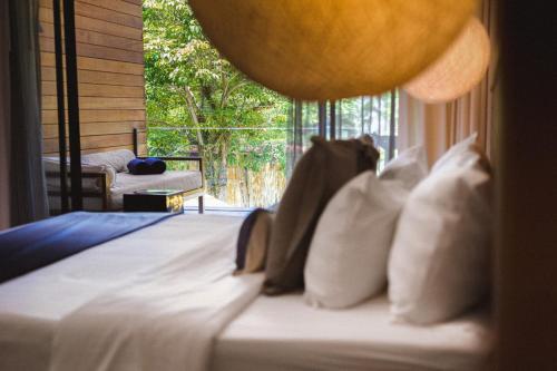 a bed with white pillows in a room with a window at Sichon Cabana Beach Resort in Sichon