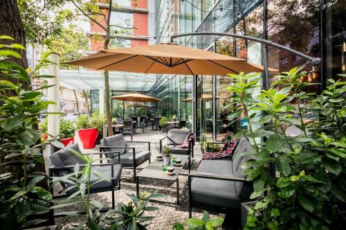 a patio with chairs and an umbrella and plants at Vienna House by Wyndham Andel's Prague in Prague