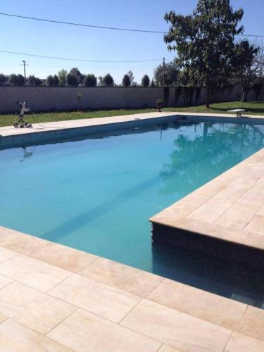 une piscine avec de l'eau bleue dans une cour dans l'établissement corps de ferme dans belle propriete avec chiens et chevaux, à Venizy