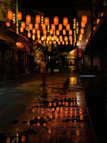 a person walking down a street at night with lanterns at Nost algia S Hotel Hangzhou West Lake & Lingyin Temple 时光漫步S酒店杭州西湖店 Free laundry service, Free fresh ground coffee in Hangzhou