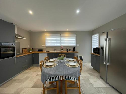 une cuisine avec une table avec des chaises et un réfrigérateur dans l'établissement Maison à la chaume proche plage sauvage 3chambres, à Les Sables-dʼOlonne