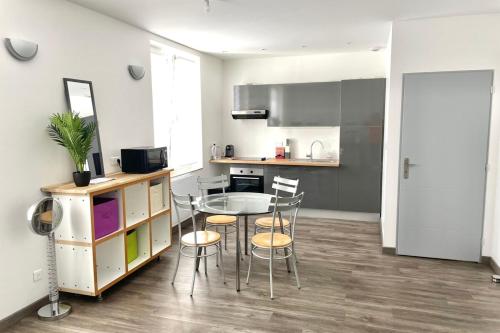 una cucina con un tavolo e sedie in una stanza di Le Dominicains appartement au calme aux portes de la Place Stanislas a Nancy