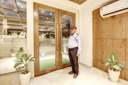 a man in uniform standing in front of a door at Marks Hotel & Banquet in Noida