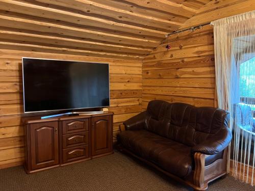 a living room with a couch and a flat screen tv at Vosylių kaimo turizmo sodyba in Kazlų Rūda