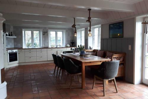 une cuisine et une salle à manger avec une table et des chaises en bois dans l'établissement Föhrhaus, Einzelhaus, Knickrehm, à Oldsum