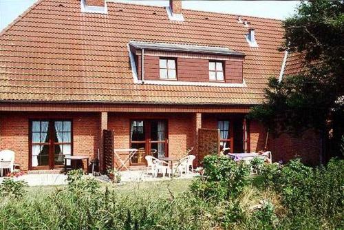una casa in mattoni rossi con tavolo e sedie di Austernfischer, Reihenhaus Guatingwai 12 FH 2 a Goting
