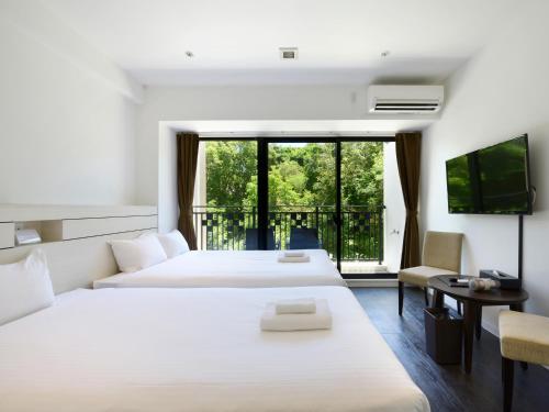 a hotel room with two beds and a balcony at Karry CONDO CHURAUMI in Motobu