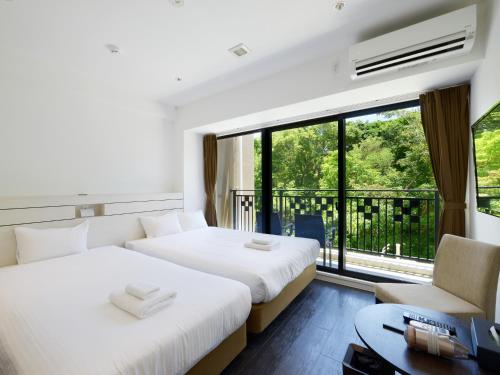 two beds in a room with a window at Karry CONDO CHURAUMI in Motobu