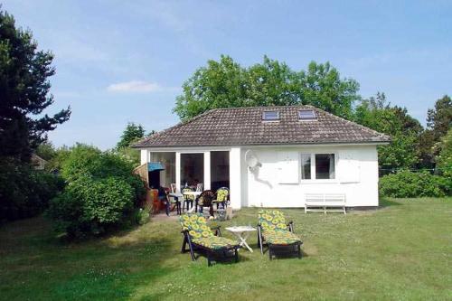a white house with chairs and a table in a yard at Strandhaus mit Kaminofen Bungalow in Goting