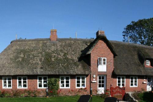 a large red brick house with a thatched roof at Skriiwers Hüüs, Hausteil in Alkersum